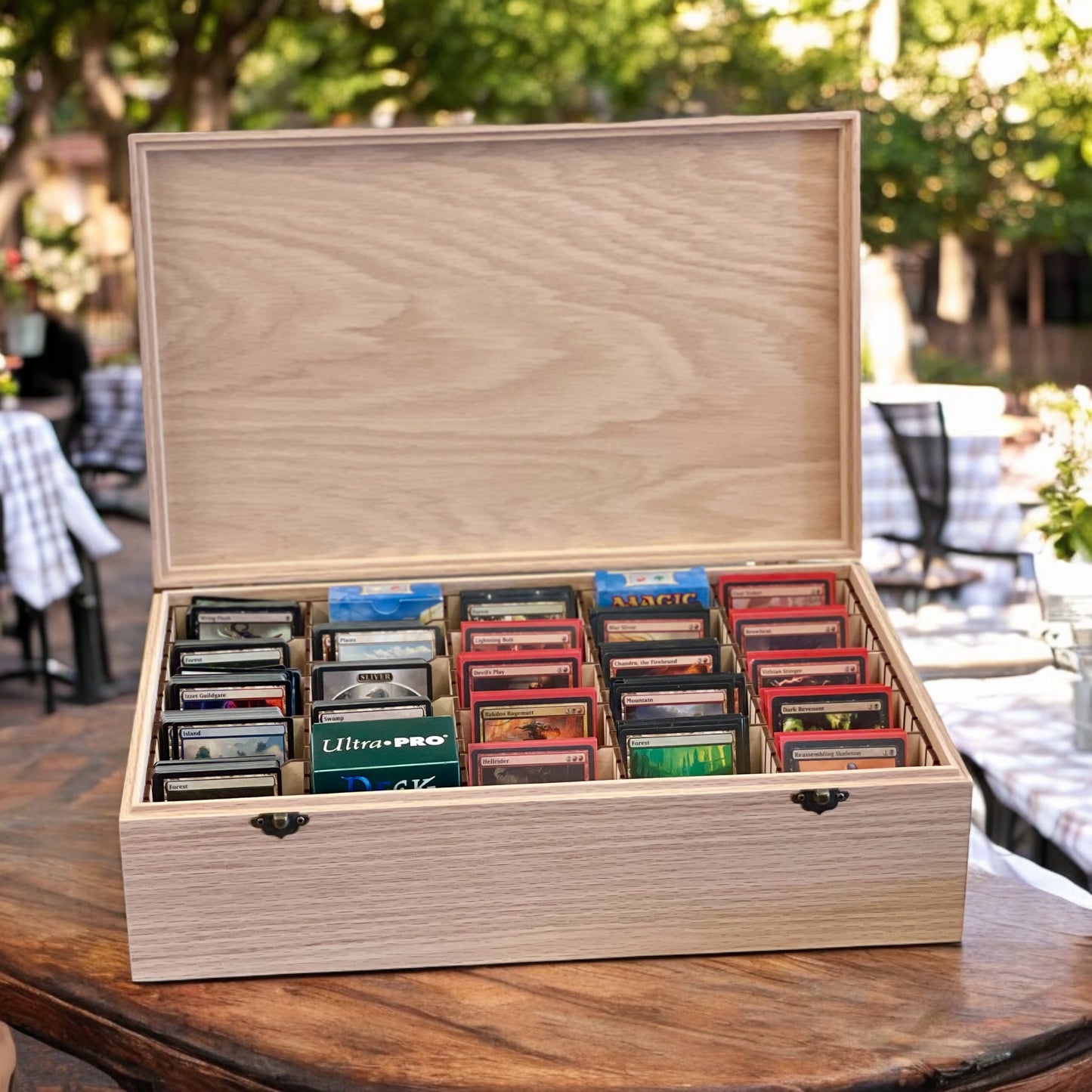 Wooden MTG card storage box with compartments holding card packs on a wooden table outdoors.