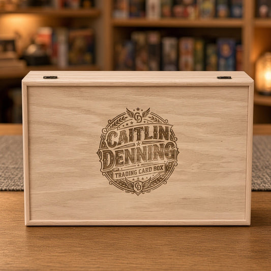 Red Oak 5-row wooden card storage box with a custom engraved name badge on the lid, on a table in front of a game shelf