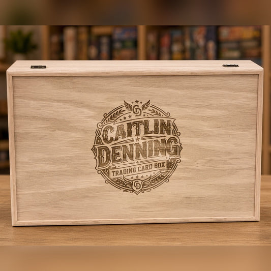 Red Oak 5-row wooden card storage box with a custom engraved name badge on the lid, on a table in front of a game shelf