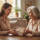 Woman presenting a wooden tea box to an elderly woman in a warm indoor setting.