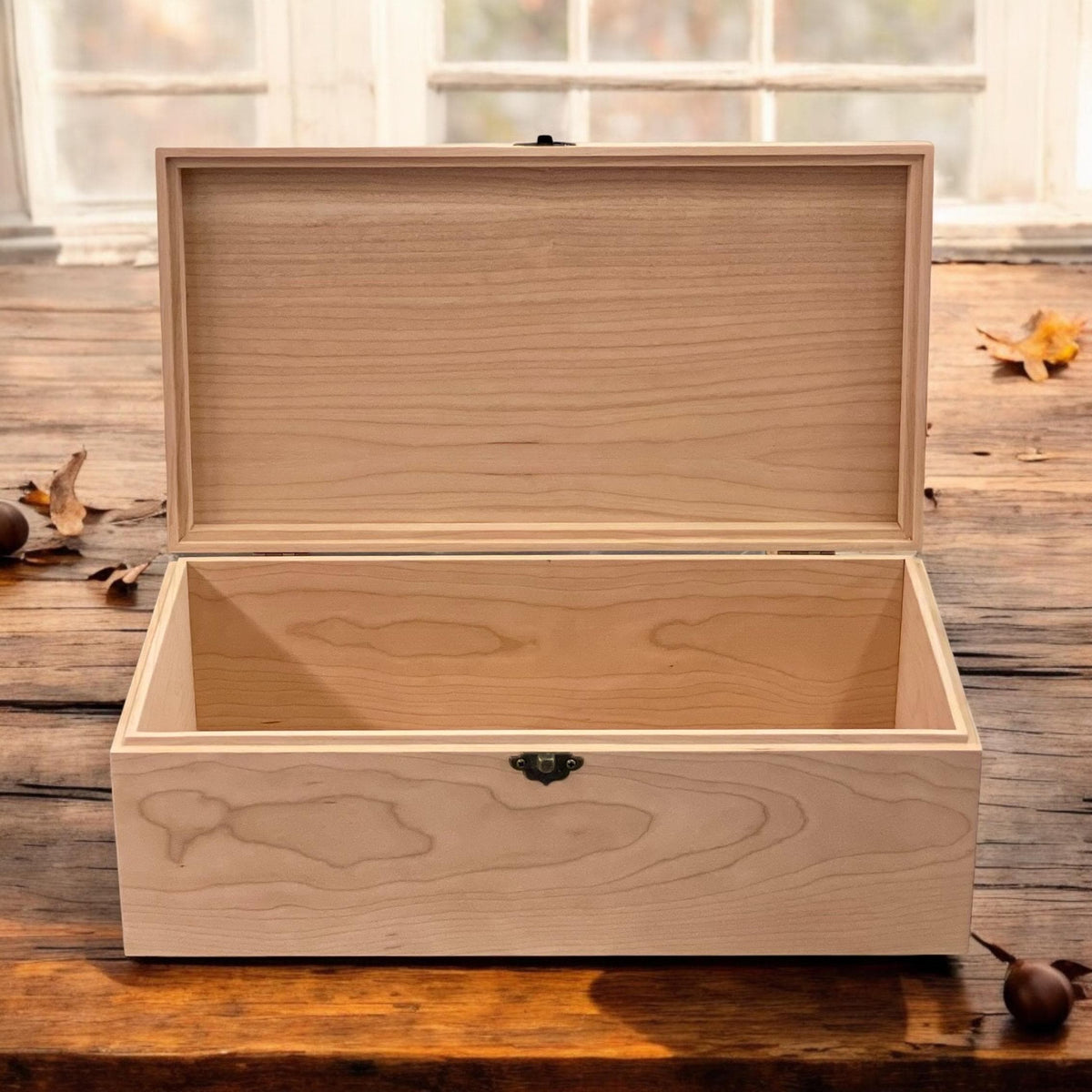 Front view of an open wooden memory box with hinged lid and empty interior on a weathered table
