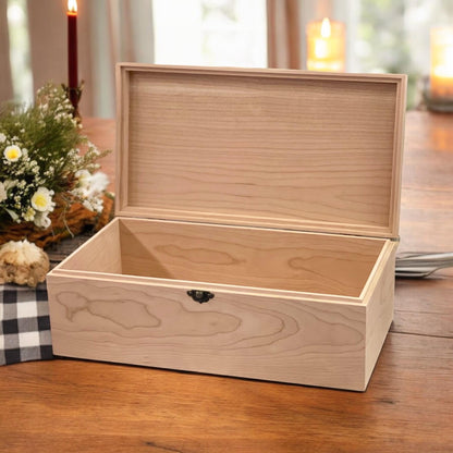 Open maple wooden memory box with hinged lid and empty interior on a table with flowers and candles