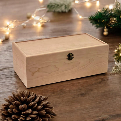 Closed wooden keepsake box with a front latch on a table with string lights, greenery and a pinecone